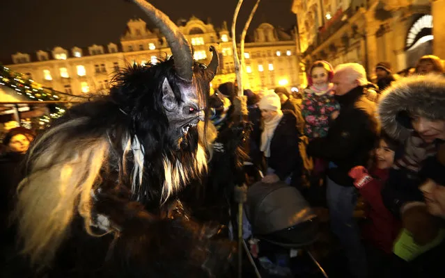 A street actor dressed as a devil frightens children in downtown Prague in Prague, Czech Republic, Monday, December 5, 2016. On the eve of St. Nicholas, Czechs traditionally celebrate by dressing up as Devils, Angels and St. Nicholas, and visiting children in their homes handing out small presents, coal, potatoes or other gifts. (Photo by Petr David Josek/AP Photo)