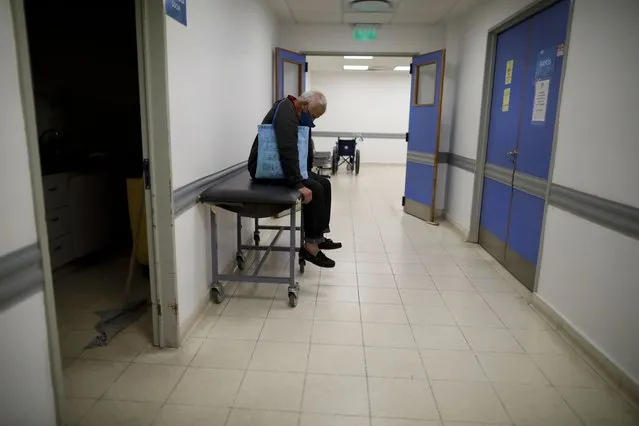 A man sits in a corridor as he waits for news of his wife who is suspected of having COVID-19 at the Dr. Norberto Raul Piacentini Hospital in Lomas de Zamora, Argentina, Saturday, May 1, 2021. (Photo by Natacha Pisarenko/AP Photo)