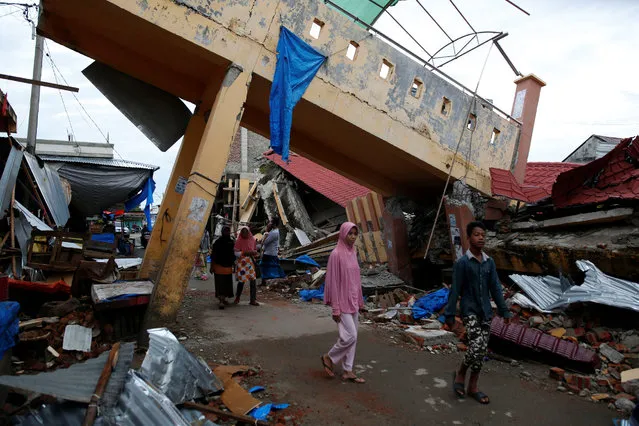 People walk past damaged buildings near the market following this week's strong earthquake in Meureudu,  Pidie Jaya, Aceh province, Indonesia December 9, 2016. (Photo by Darren Whiteside/Reuters)