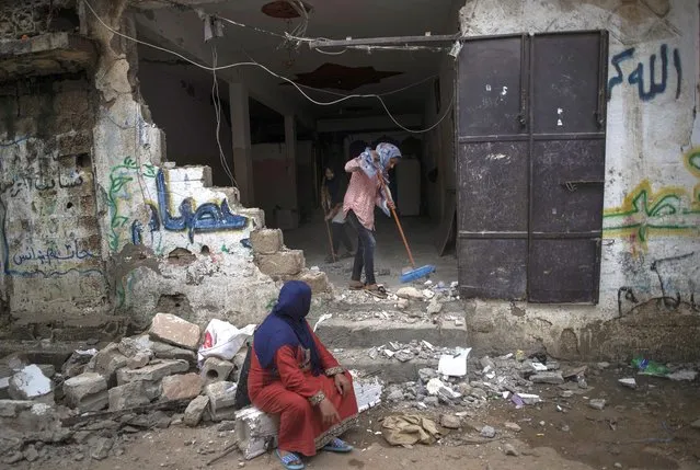 A Palestinian family remove the rubble from their damaged home following a cease-fire reached after an 11-day war between Gaza's Hamas rulers and Israel, in town of Beit Hanoun, northern Gaza Strip, Friday, May 21, 2021. (Photo by Khalil Hamra/AP Photo)