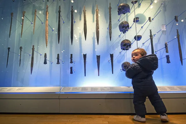 A young visitor looks at human skulls and weapons found in the River Thames dating 1300-1000BC at the Museum of London, which is reopening following the further easing of lockdown restrictions in England, in London, Wednesday May 19, 2021. (Photo by Victoria Jones/PA Wire via AP Photo)