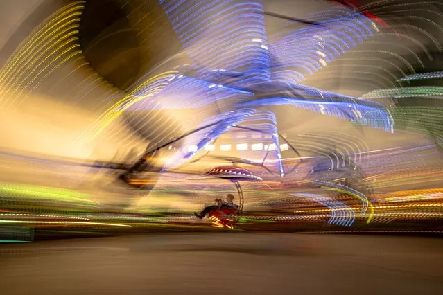 A person enjoys a ride at a fair in Hagioaica, Romania, Saturday, September 16, 2023. For many families in poorer areas of the country, Romania's autumn fairs, like the Titu Fair, are one of the very few still affordable entertainment events of the year. (Photo by Alexandru Dobre/AP Photo)