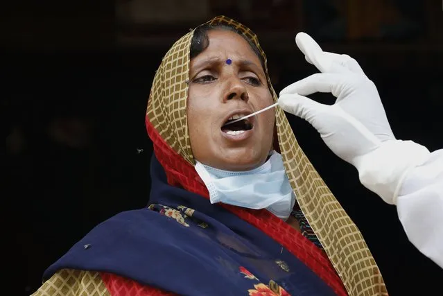 A health worker takes a swab sample of a woman to test for COVID-19 in Kusehta village north of Prayagraj, India, Saturday, May 29, 2021. (Photo by Rajesh Kumar Singh/AP Photo)