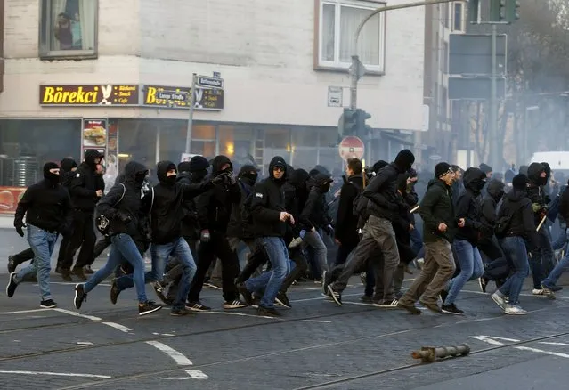 Anti-capitalist “Blockupy” protesters run on a street near the European Central Bank (ECB) building before the official opening of its new headquarters in Frankfurt March 18, 2015. (Photo by Michael Dalder/Reuters)