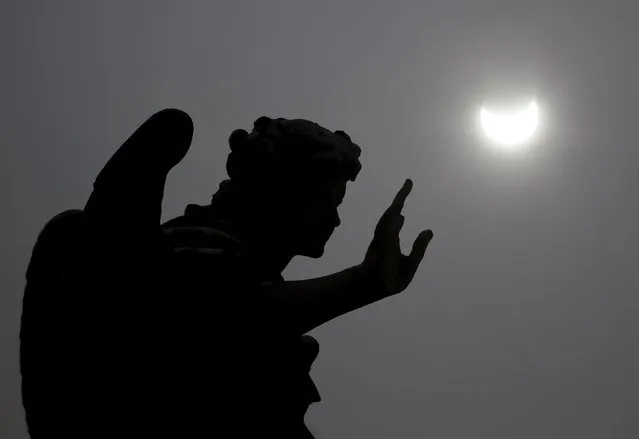 A partial solar eclipse is seen over a statue at the Mausoleum of Hadrian, usually known as Castel Sant'Angelo, in Rome March 20, 2015. (Photo by Yara Nardi/Reuters)