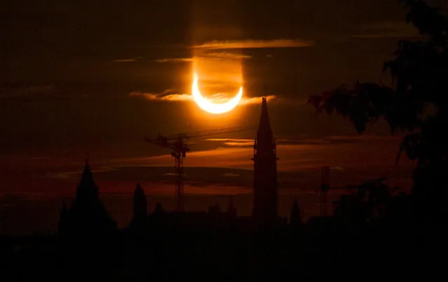 An annular solar eclipse rises over construction cranes and the Peace Tower on Parliament Hill in Ottawa on Thursday, June 10, 2021. (Photo by Sean Kilpatrick/The Canadian Press via AP Photo)