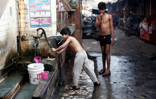 A boy uses a hand-pump to collect water for bathing at a market area on a cold winter morning in the old quarters of Delhi, India, December 27, 2018. (Photo by Adnan Abidi/Reuters)