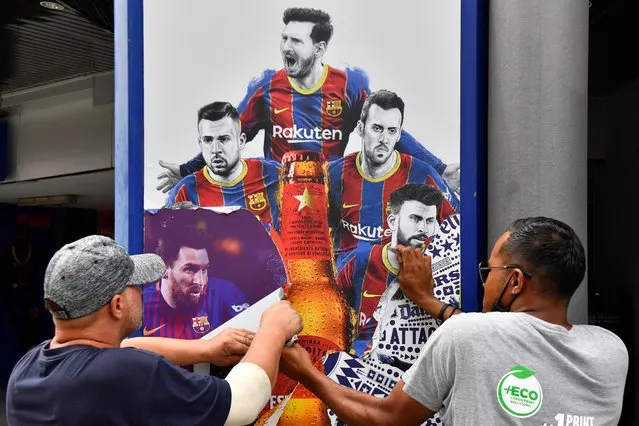 Workers remove posters featuring Barcelona's departing Argentinian forward Lionel Messi at the Camp Nou stadium in Barcelona on August 10, 2021. France is waiting impatiently for Lionel Messi with supporters gathering outside Paris Saint-Germain's ground hoping to see the Argentine who is expected to join the Qatar-owned club after his exit from Barcelona. (Photo by Pau Barrena/AFP Photo)