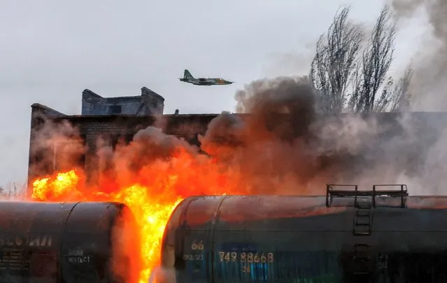 A Russian fighter jet flies above a railway junction on fire following recent shelling in the course of Russia-Ukraine conflict in the town of Shakhtarsk (Shakhtyorsk) near Donetsk, Russian-controlled Ukraine on October 27, 2022. (Photo by Alexander Ermochenko/Reuters)