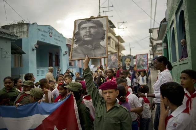 A child holds up a picture of revolutionary hero Ernesto "Che" Guevara as others, background, carry portraits of Fidel Castro and independence hero Jose Martí during a caravan marking the 57th anniversary of the arrival of Fidel Castro an his rebel army in Regla,  outskirts of Havana, Cuba, Friday, January 8, 2016. Castro and his rebels arrived in Havana via caravan on Jan. 8, 1959, after toppling dictator Fulgencio Batista. (Photo by Ramon Espinosa/AP Photo)