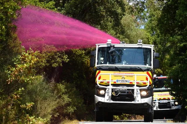Firefighters spray fire-retardant from a fire tender to avoid rework on small fireplaces due to wind, during wildfire in La Garde-Freinel in the department of Var, southern France, on August 20, 2021. After five days of fierce fighting by firefighters against the worst fire of the year in France, which killed two people, the fire is “fixed” in the hinterland of the Var region, but “not extinguished” and the emergency services fear that the wind will strengthen. (Photo by Sylvain Thomas/AFP Photo)