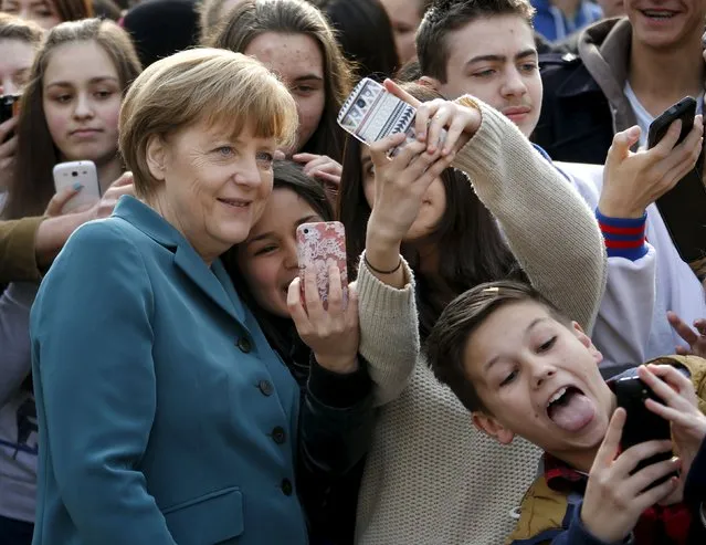 Pupils take selfies with German Chancellor Angela Merkel, as she arrives for a visit at Robert-Jungk Europe high school as part of the Europe-Project Day, in Berlin in this March 31, 2014 file photo. (Photo by Fabrizio Bensch/Reuters)