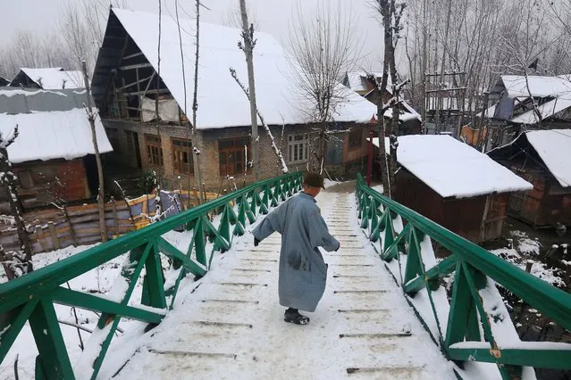 A young Kashmiri boy slides down a snow covered wooden bridge after fresh snowfall, in the outskirts of Srinagar, India, Thursday, January 9, 2014. Traffic on the 300 kilometers (186 miles) long Jammu-Srinagar national highway has been suspended due to heavy snowfall, according to news reports. (Photo by Dar Yasin/AP Photo)