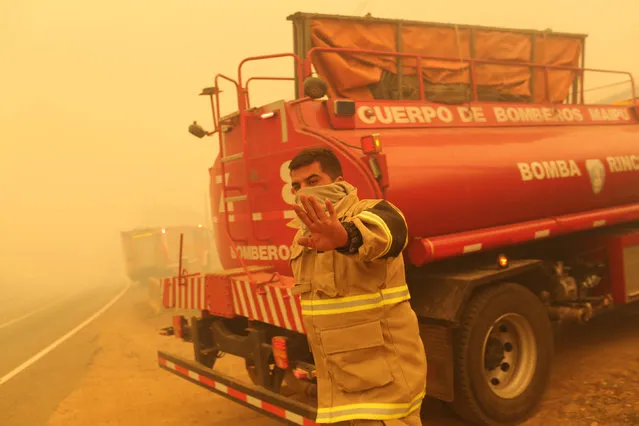 A firefighter gestures while standing near his firetruck as the worst wildfires in Chile's modern history ravaged wide swaths of the country's central-south regions, in Santa Olga, Chile January 26, 2017. (Photo by Pablo Sanhueza/Reuters)