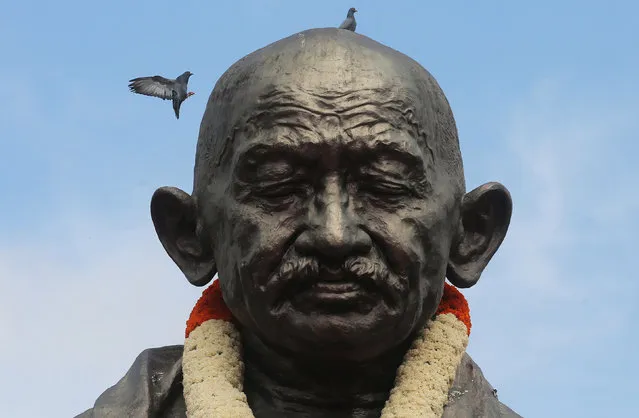 Pigeons fly over the Mahatma Gandhi statue at Vidhana Soudha, the seat of the state legislature of Karnataka, in Bangalore, India 02 October 2021. India commemorates the 152nd birth anniversary of Indian lawyer Mohandas Karamchand Gandhi, commonly known as Mahatma Gandhi, on 02 October 2021. (Photo by Jagadeesh N.V./EPA/EFE)