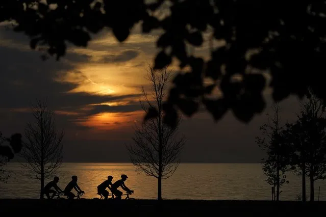 Four cyclists navigate the bike trail along Lake Michigan shortly after sunrise Friday, August 27, 2021, in Chicago. (Photo by Charles Rex Arbogast/AP Photo)