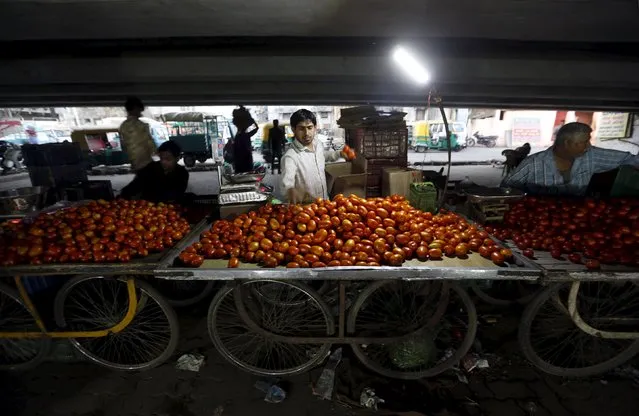 A roadside vendor arranges tomatoes on his handcart as he waits for customers under a flyover in Ahmedabad, India, March 8, 2016. (Photo by Amit Dave/Reuters)