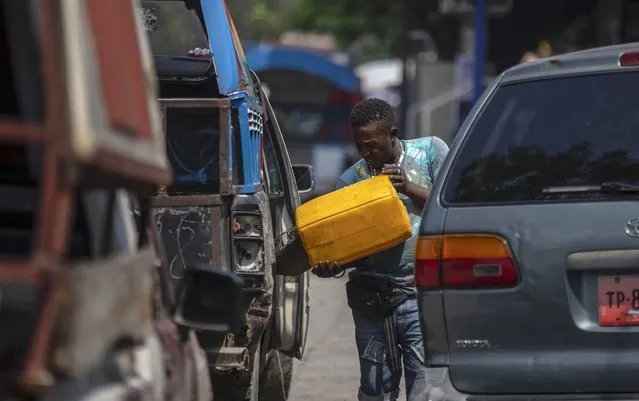 A man pours fuels into the gas tank of his car, on a street in Port-au-Prince, Haiti, Sunday, October 17, 2021. (Photo by Joseph Odelyn/AP Photo)