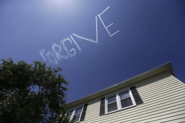 In this May 1, 2015 photo, the message “FORGIVE”, made by skywriter Nathan Hammond, floats above a home in New Orleans, during the New Orleans Jazz & Heritage Festival. (Photo by Gerald Herbert/AP Photo)