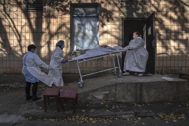 Medical staff members transport a body of a patient who died of coronavirus at the morgue of the city hospital 1 in Rivne, Ukraine, Friday, October 22, 2021. (Photo by Evgeniy Maloletka/AP Photo)