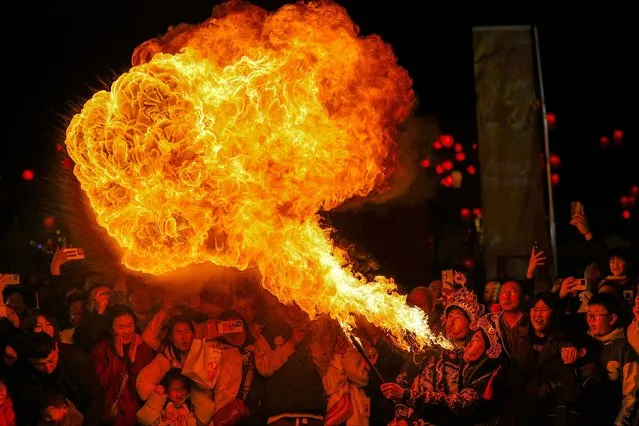 The photo taken on February 17, 2024 shows a Chinese folk artist blowing fire from his mouth during a performance to celebrate the Lunar New Year of the Dragon on a street in Luoyang, in central China's Henan province. (Photo by AFP Photo/China Stringer Network)