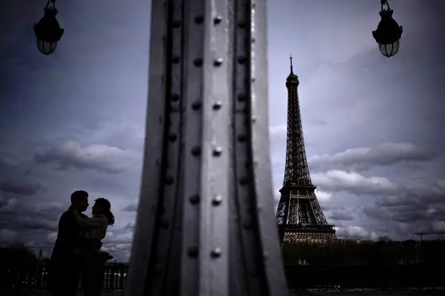 A couple kisses on the Bir Hakeim bridge with the Eiffel Tower in the background in Paris, on March 29, 2024. (Photo by Julien de Rosa/AFP Photo)
