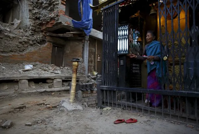 A woman walks out from a temple after offering daily prayers near a collapsed house, a month after the April 25 earthquake in Kathmandu, Nepal May 25, 2015. (Photo by Navesh Chitrakar/Reuters)