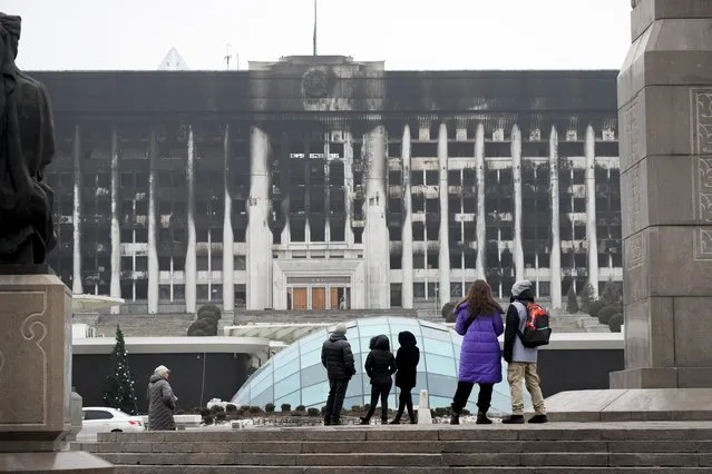 People look at the city hall building in the central square blocked by Kazakhstan troops and police in Almaty, Kazakhstan, Tuesday, January 11, 2022. Authorities in Kazakhstan say nearly 8,000 people were detained by police during protests that descended into violence last week and marked the worst unrest the former Soviet nation has faced since gaining independence 30 years ago. (Photo by AP Photo/Stringer)