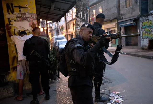 Police officers search residents for guns during an operation against drug gangs in the Mare slum complex in Rio de Janeiro, Brazil, Sunday, March 30, 2014. The Mare complex of slums, home to about 130,000 people and located near the international airport, is the latest area targeted for the government's “pacification” program, which sees officers move in, push out drug gangs and set up permanent police posts. (Photo by Silvia Izquierdo/AP Photo)