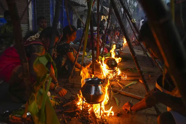 Tamil women cook special food to celebrate the harvest festival of Pongal at Dharavi, one of the world's largest slums, in Mumbai, India, Friday, January 14, 2022. This Hindu celebration, held according to the solar calendar, marks the beginning of the sun's northward movement and is considered to be auspicious. (Photo by Rafiq Maqbool/AP Photo)