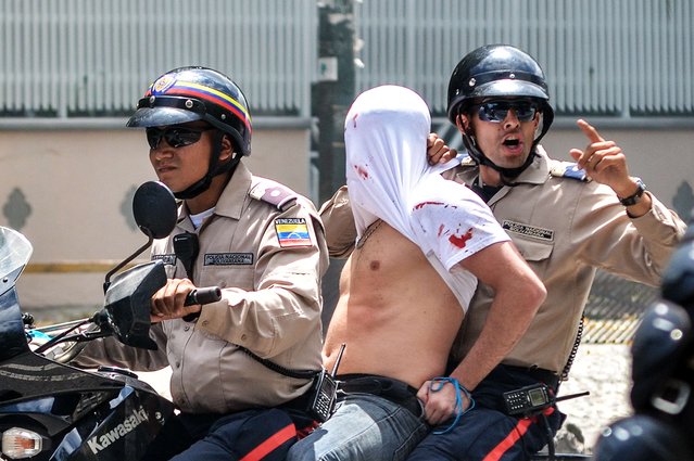 Members of the national police arrest a man during a protest against Venenzuelan President Nicolas Maduro in Caracas on April 6, 2014. The Government of Venezuelan President Nicolas Maduro on Sunday rejected the statements of Spanish Foreign Minister Jose Manuel Garcia-Margallo, who said that “the climate of reconciliation has been broken” in Venezuela as the wave of opposition protests continues in the South American country. (Photo by Carlos Becerra/AFP Photo)
