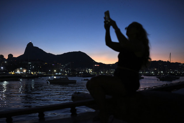 A person holds a cellphone on a boat to attend Madonna's concert, in Rio de Janeiro, Brazil on May 4, 2024. (Photo by Tita Barros/Reuters)