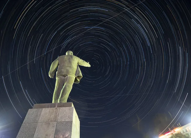 The International Space Station (ISS) moves along its orbit above at the Russian leased Baikonur cosmodrome, Kazakhstan, Thursday, July 18, 2019, with a statue of Soviet Union founder Vladimir Lenin in the foreground. Circular star tracks around the Polar Star and tracks of the ISS is the result of the camera multiple exposure with a total duration of two hours. The new Soyuz mission to the International Space Station (ISS) is scheduled on Saturday, July 20 with U.S. astronaut Andrew Morgan, Russian cosmonaut Alexander Skvortsov and Italian astronaut Luca Parmitano. (Photo by Dmitri Lovetsky/AP Photo)