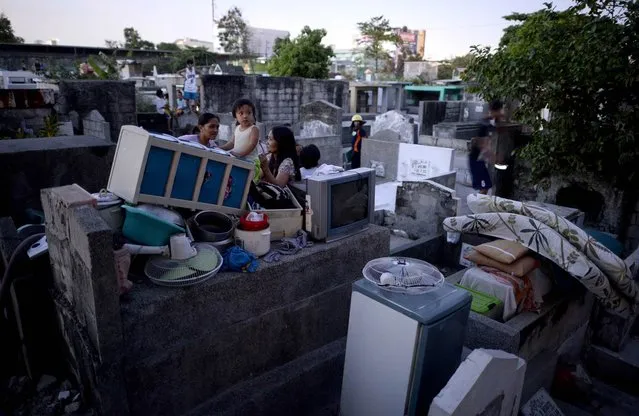 Residents stay on tombs after their makeshift houses were hit by fire that swept over a shanty community inside a public cemetery in Manila on May 4, 2016. No one was hurt in the fire, according to initial reports. (Photo by Noel Celis/AFP Photo)