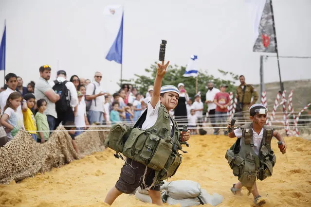 An Israeli boy dresses wearing a military vest  throws a mock granade during a traditional military weapon display to mark the 66th anniversary of Israel's Independence at the West Bank settlement of Efrat on May 6, 2014 near the biblical city of Bethlehem. (Photo by Gali Tibbon/AFP Photo)