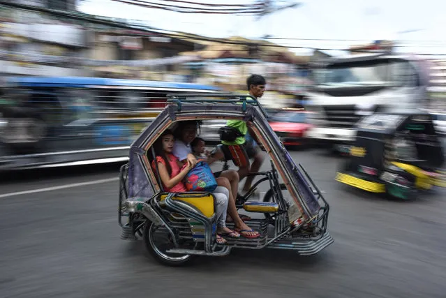 A Filipino family rides in a traditional tricycle taxi ahead of the presidential and vice presidential elections in Tondo, Manila on May 7, 2016. Mass murder advocate Rodrigo Duterte heads into final rallies of an extraordinary Philippine presidential campaign as the shock favourite, but with rivals still having a chance to counter his profanity-laced populist tirades. (Photo by Mohd Rasfan/AFP Photo)