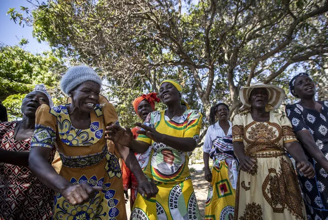 A woman wearing a dress with the face of former president Robert Mugabe, joins with others to sing political songs of his ZANU-PF party, at his house in his home village of Kutama, in Zimbabwe Wednesday, September 11, 2019. The body of Mugabe is being flown to the capital, Harare, on Wednesday where it will be displayed at historic locations for several days before burial at a location still undecided because of friction between the ex-leader's family and the government. (Photo by Ben Curtis/AP Photo)