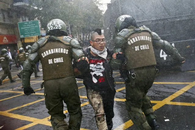 A student is detained by police after throwing an object at them during a protest march demanding the government overhaul the education funding system that would include canceling their student loan debt, in Santiago, Chile, Tuesday, May 9, 2017. Some students stay in debt for up to 20 years after completing their studies. (Photo by Esteban Felix/AP Photo)