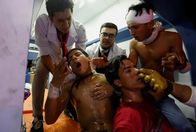 Demonstrators who were affected by tear gas receive treatment from medical crew during a protest over corruption, lack of jobs, and poor services, in Baghdad, Iraq on October 29, 2019. (Photo by Wissm al-Okili/Reuters)