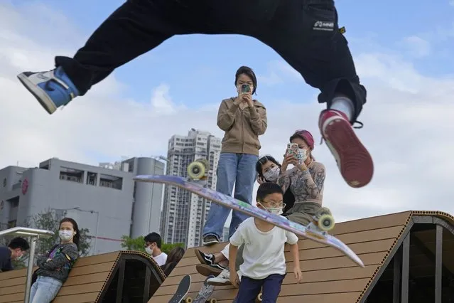 Kids wearing masks watch a teenager flipping his skateboard in an “ollie” at a park in Hong Kong, Wednesday, March 30, 2022. (Photo by Kin Cheung/AP Photo)