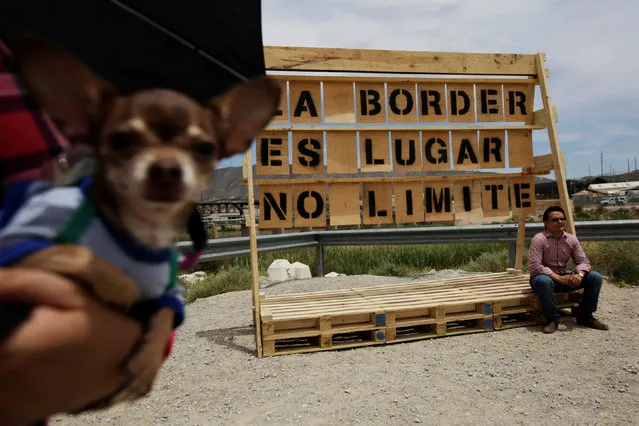 A man sits on a wooden sign with a bilingual phrase that is part of a project initiated by Mexican activists known as “Letters A La Border” to reflect on the importance of bilateral relationship between Mexico and U.S., near a Chihuahua dog, at the border between both countries in Ciudad Juarez, Mexico May 14, 2017. The sign reads: “The border is a place with no limit”. (Photo by Jose Luis Gonzalez/Reuters)