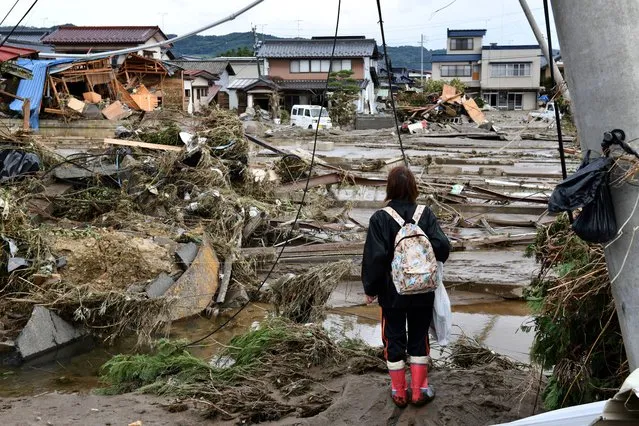 A woman looks at flood-damaged homes in Nagano on October 15, 2019, after Typhoon Hagibis hit Japan on October 12 unleashing high winds, torrential rain and triggered landslides and catastrophic flooding. Rescuers in Japan worked into a third day on October 15 in an increasingly desperate search for survivors of a powerful typhoon that killed nearly 70 people and caused widespread destruction. (Photo by Kazuhiro Nogi/AFP Photo)