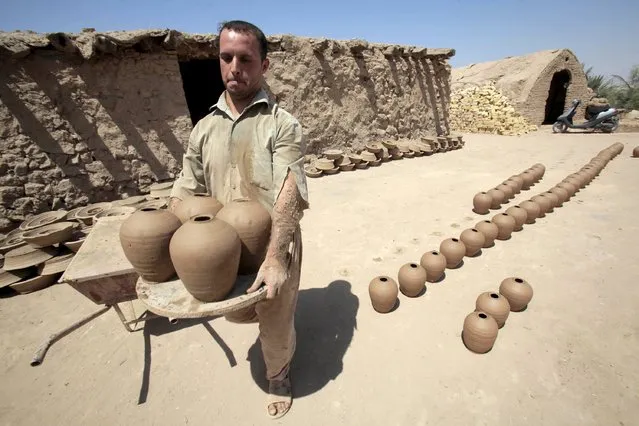 A man carries moulds clay at a workshop in Najaf, south of Baghdad, July 23, 2015. (Photo by Alaa Al-Marjani/Reuters)