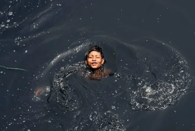 An Indian youth swims in the polluted Yamuna river amid rising temperatures in New Delhi on May 9, 2017. According to the Central Pollution Control Board (CPCB) which monitors the water quality of the Yamuna in New Delhi, 70% of the pollution of the river is from untreated sewage while the remainder is from industrial sources, agricultural run-off, and domestic garbage. (Photo by Prakash Singh/AFP Photo)