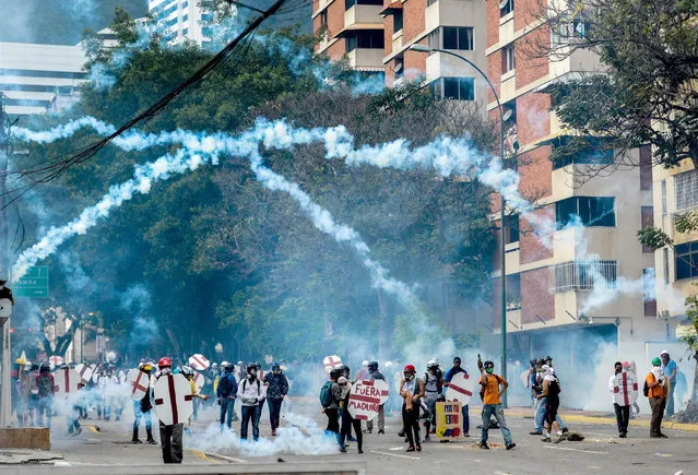 Opposition demonstrators and riot police clash during a protest against Venezuelan President Nicolas Maduro, in Caracas on May 3, 2017. Venezuelan police fired tear gas and hooded protesters hurled Molotov cocktails as thousands rallied Wednesday in anger at President Nicolas Maduro's plan to rewrite the constitution. At least one protester caught fire and two opposition lawmakers were among various people injured, AFP reporters at the scene said. (Photo by Federico Parra/AFP Photo)