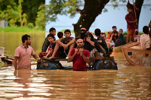 People wade through flood waters in Feni on August 23, 2024. Floods triggered by torrential rains have swamped a swath of low-lying Bangladesh, disaster officials said on August 22, adding to the new government's challenges after weeks of political turmoil. (Photo by Munir Uz Zaman/AFP Photo)