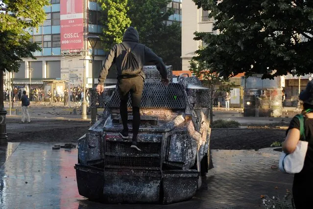 A demonstrator climbs on a riot police vehicle during a protest against Chile's government in Concepcion, Chile, December 9, 2019. (Photo by Jose Luis Saavedra/Reuters)