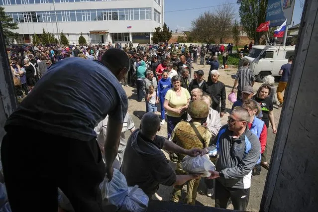 Local civilians gather to get humanitarian aid distributed by Donetsk People Republic Emergency Situations Ministry in Berdyansk, in territory under the government of the Donetsk People's Republic, eastern Ukraine, Saturday, April 30, 2022. This photo was taken during a trip organized by the Russian Ministry of Defense. (Photo by AP Photo/Stringer)