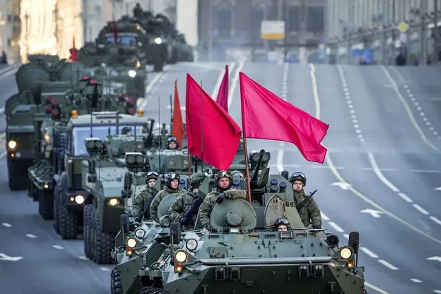 Spectators watch as Russian armored vehicles decorated with red flags roll along Tverskaya street toward Red Square to attend a rehearsal for the Victory Day military parade in Moscow, Russia, Wednesday, May 4, 2022. (Photo by Alexander Zemlianichenko/AP Photo)