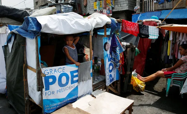 A boy stands at the window of a shanty that was built with campaign posters of recent presidential election in Manila, Philippines May 25, 2016. (Photo by Erik De Castro/Reuters)